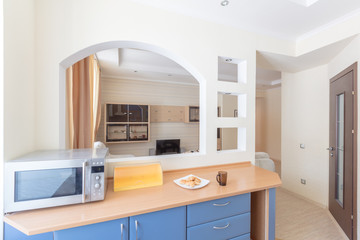 kitchen table with microwave at  window arch in wall overlooking living room