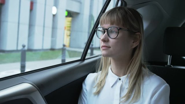 Young Businesswoman Putting on Glasses in the Imobile Car