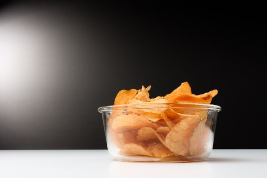 Kartoffel Chips in transparenten Glas Sch&uuml;ssel vor schwarz / wei&szlig; Hintergrund