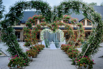Naklejka premium Path to wedding altar made of archs in shape of hearts and covered with flowers and greenery
