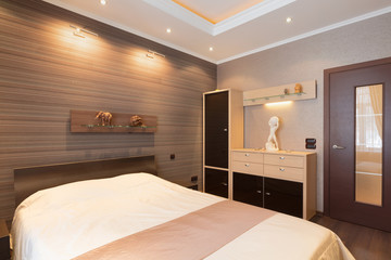 bedroom in brown tones with designer details on wall and  door