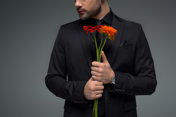 Cropped view of male with bouquet of flowers isolated on grey, international womens day concept