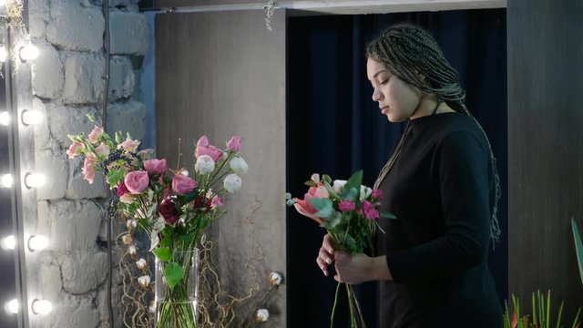 Female afro-american florist making a bouquet of fresh flowers in a florist's. 4K