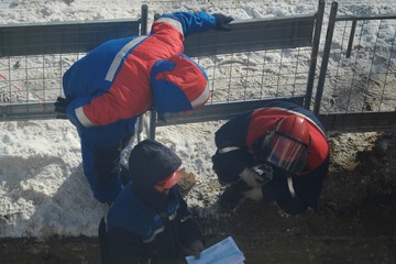 Working men in the form of standing around a sand pit 