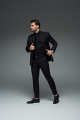 Young stylish man posing in formal suit on grey