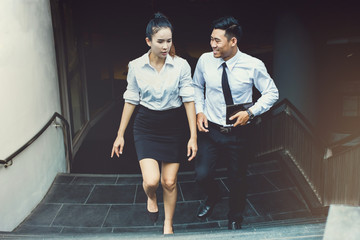 Asian businessman and businesswoman or Confident business partners walking  up on staircase office...
