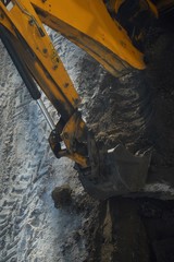 Yellow bulldozer digs a pit of sand 
