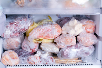 Refrigerator with frozen food. Open fridge freezer (meat, milk, vegetables).