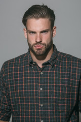 Fashionable confident man with beard in checkered shirt. Advertising, clothes and people concept - respectable serious stylish man isolated on gray background. Luxury, men's beauty, fashion, style.