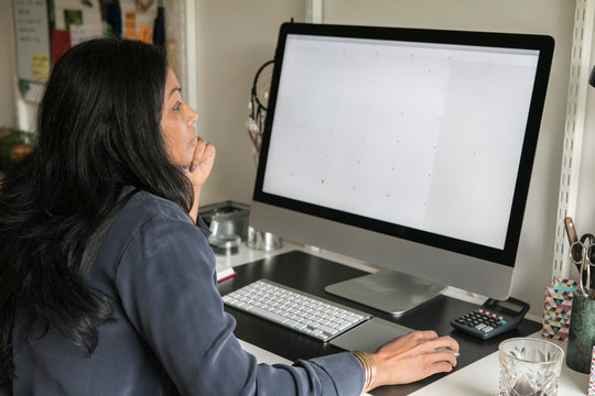 Side view of businesswoman using computer while sitting at home office