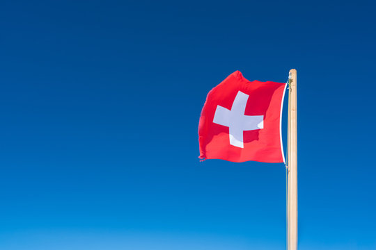 Flag of Switzerland against the background of the blue sky.