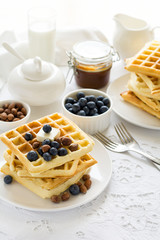 Healthy breakfast. Belgian waffles with butter, blueberry and nuts on white tablecloth. Selective focus