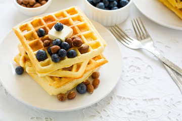 Healthy breakfast. Belgian waffles with butter, blueberry and nuts on white tablecloth. Selective focus