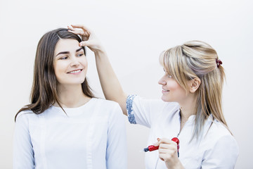 Beautician woman and her lucky client model in permanent eyebrow makeup and face care office