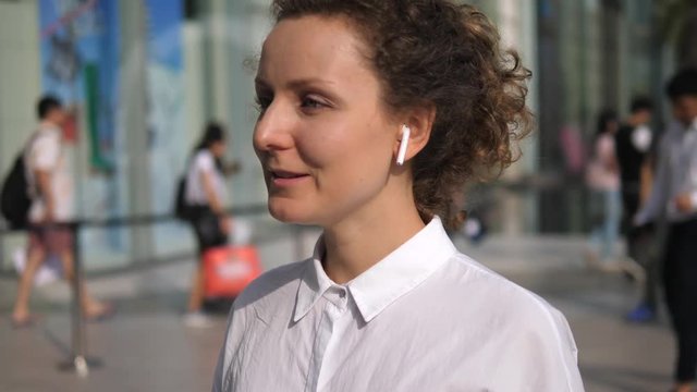 Woman Speaking By Phone In Wireless Earphones In City