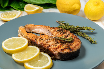 Salmon fillet. Grilled salmon with herb and lemon on plate. Fish roasted on a wooden background.