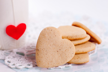 cookies in the shape of a heart on a gray background and a white cup in the background, minimalism, a concept of cooking, baking, a symbol of love