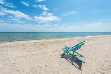 Fototapeta na wymiar Beach chairs on the white sand with cloudy blue sky and sun