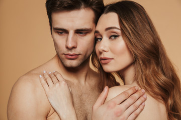 Portrait of confident beautiful lovers hugging isolated over beige