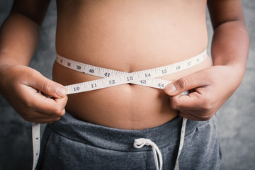 Portrait fat boy measuring tape of stomach,healthy and lose weight concept ,selective and soft focus