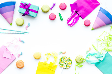 Birthday party accessories. Gift box, paper bag, party hat, sweets, confetti on white background top view copy space