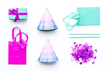 Birthday party accessories. Gift box, paper bag, party hat, confetti on white background top view copy space