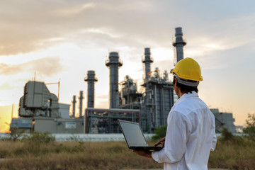 Engineer is checking gas turbine electric power plant by notebook with twilight