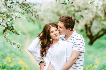 Fototapeta premium Close up portrait of lovely future parents during sunset on nature apple tree background