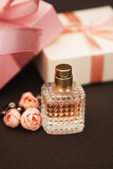 Women's Pink Perfume in Beautiful Bottle and Artificialt Flowers Bracelet on Brown Background with gift boxes on Background.