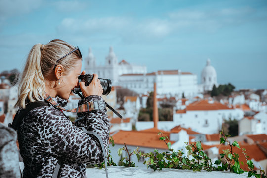 Traveler woman make a picture of Lisbon cityscape. The National Pantheon and the towels of Vicente de Fora come into view. Roofs of Lisbon