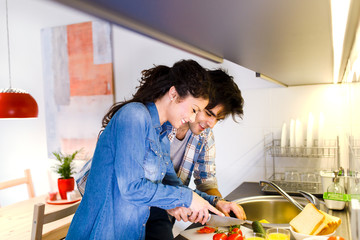 Young couple making breakfast early in the morning in the kitchen and having a good time.