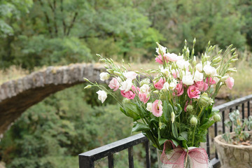 Ramo de flores silvestres en un paisaje de campo con un puente románico al fondo en Sant Sadurni...