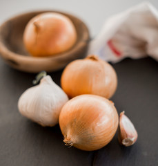 Bowl with onions and garlic with tablecloth on dark background, 