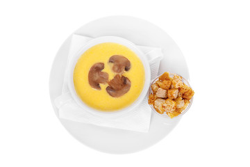 Soup puree, cream soup yellow with mushrooms, championons and crackers, dry bread. On a napkin in a white plate isolated white. Serving dishes in a cafe, restaurant, for a menu. View from above