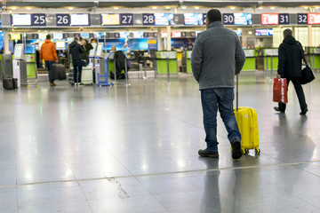 A man with a yellow suitcase at the airport goes to the terminal. Selected focus