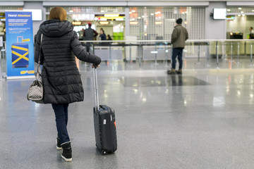 Woman with a suitcase at the airport. Selected focus