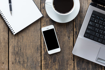 smart phone blank screen with cup coffee and computer on old wooden table top view.