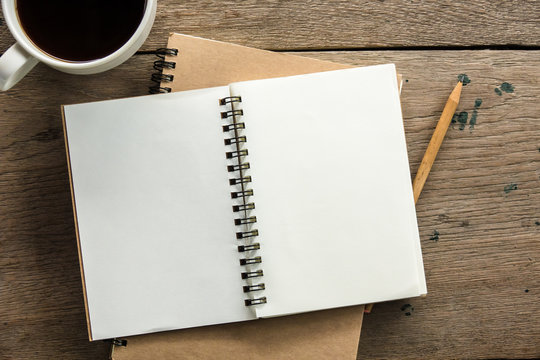 Top view of blank notebook with white coffee and natural light on wooden table.