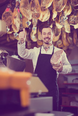 attentive male shop assistant using scales for meat in butcher&rsquo;s shop