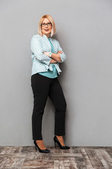 Full length image of Pleased middle-aged blonde woman in blouse