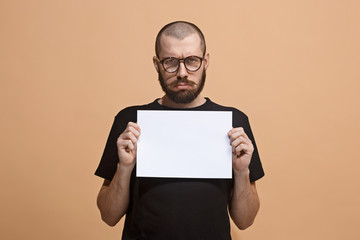 A young man holds an empty plate in his hands to fill your text. Emotional, courageous face.