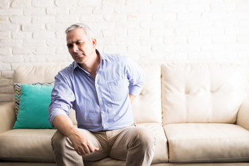 Fototapeta premium Middle aged man at home suffering from back pain