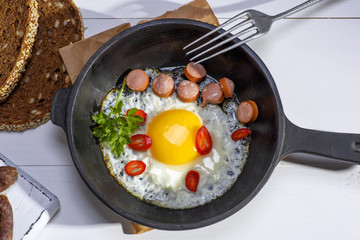  chicken egg with sausage slices in a round black cast-iron frying pan a