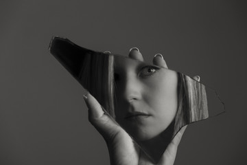 Woman looking at her face in a shard of broken mirror artistic conversion - 194303973