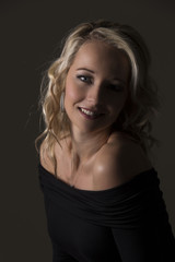 Fototapeta premium Beautiful blond woman in curly hair and black top on grey background