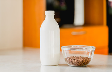 A glass bowl with cacao rice crisps and a bottle of fresh milk.