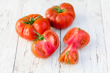 Close-up of fresh, ripe tomatoes on white wood background with copy space.