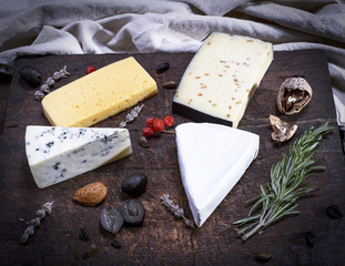 pieces of different cheeses on a brown wooden board