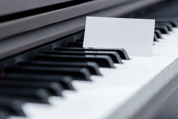 Blank business card placed between piano keyboard racings