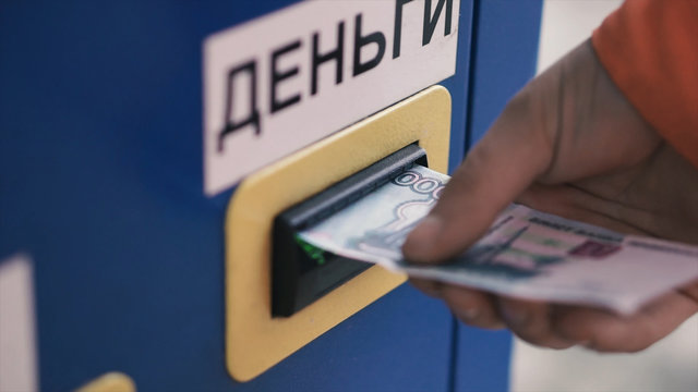 Person's hand sticks a paper money bill into the banknote bill acceptor. Clip. Bill acceptor